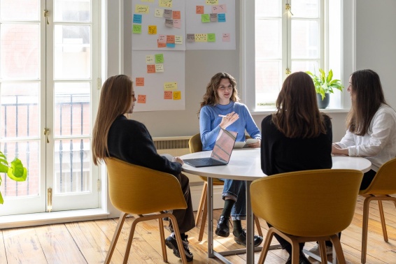 Colleagues meeting around a table with post it notes on the wall behind them.